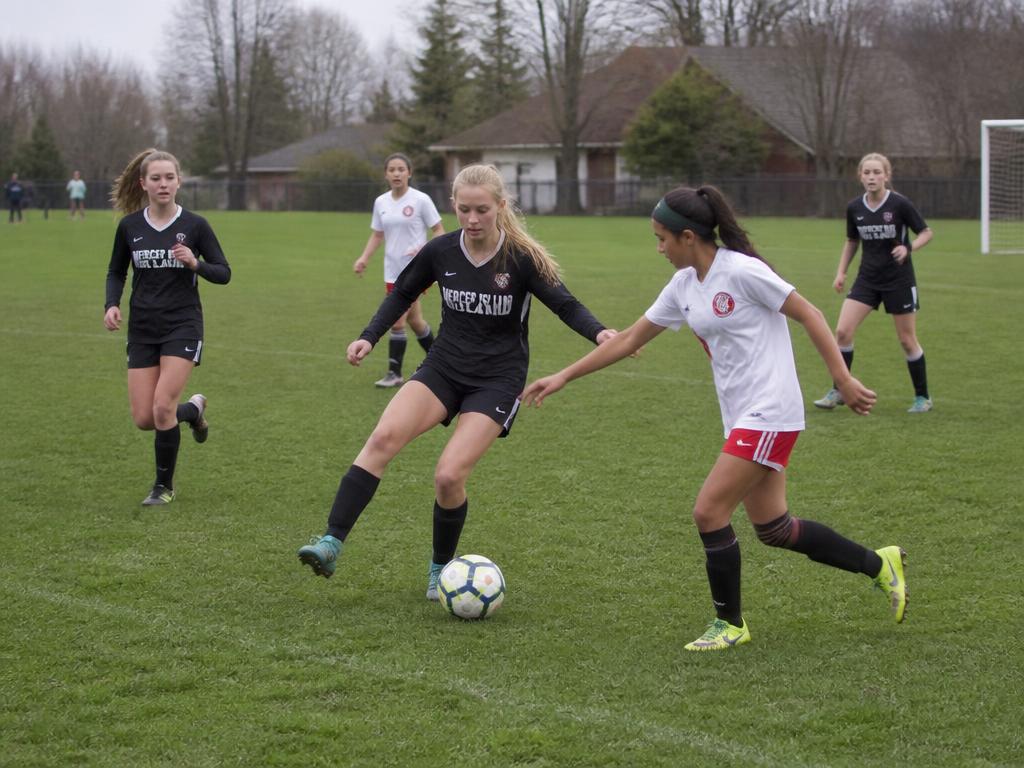 Middle school girls soccer players competing for the ball on the field